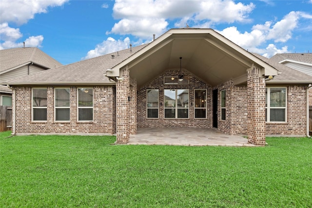back of house with roof with shingles, a yard, a patio area, and brick siding