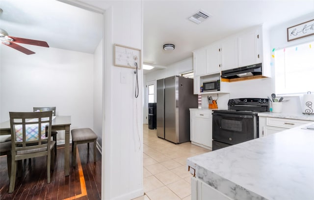 kitchen with under cabinet range hood, black / electric stove, visible vents, freestanding refrigerator, and ceiling fan