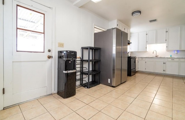 kitchen featuring light tile patterned floors, range, visible vents, freestanding refrigerator, and white cabinets