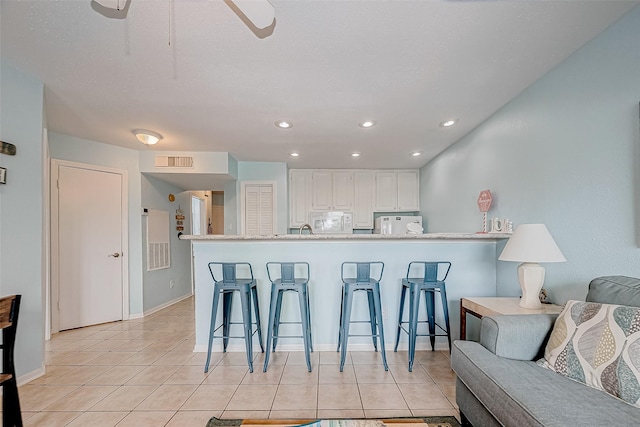 9520 Seawall Blvd Unit 126, Galveston, TX 77554 - kitchen with white appliances, visible vents, a kitchen bar, and light tile patterned floors