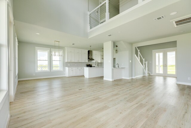 18821 Warrior Rd, Galveston, TX 77554 - unfurnished living room with french doors, healthy amount of natural light, light wood-type flooring, a towering ceiling, and recessed lighting