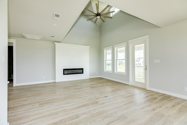 18821 Warrior Rd, Galveston, TX 77554 - unfurnished living room featuring ceiling fan, high vaulted ceiling, light wood-type flooring, a glass covered fireplace, and baseboards