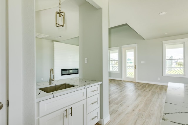 18821 Warrior Rd, Galveston, TX 77554 - kitchen with a sink, lofted ceiling, light stone countertops, light wood finished floors, and white cabinetry