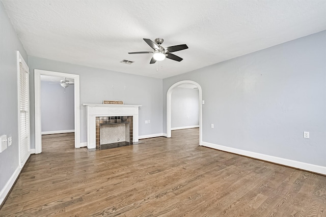 unfurnished living room featuring visible vents, arched walkways, wood finished floors, and ceiling fan