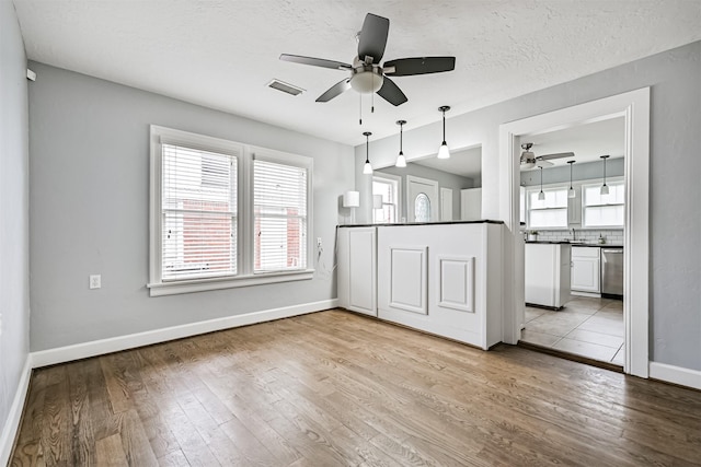 kitchen featuring visible vents, ceiling fan, wood finished floors, tasteful backsplash, and stainless steel dishwasher