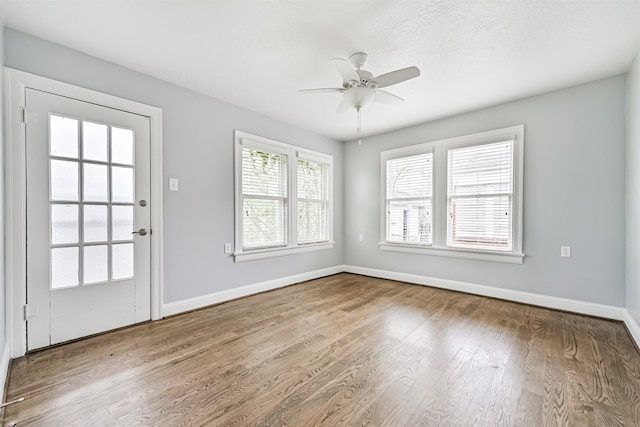 interior space with baseboards, wood finished floors, and ceiling fan