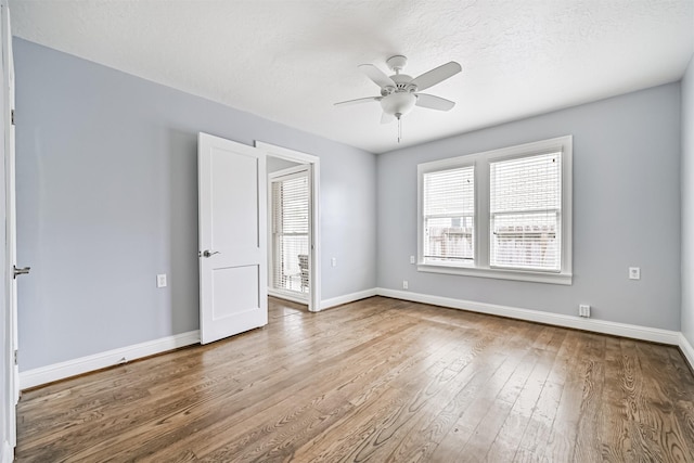 unfurnished room with wood-type flooring, a ceiling fan, baseboards, and a textured ceiling