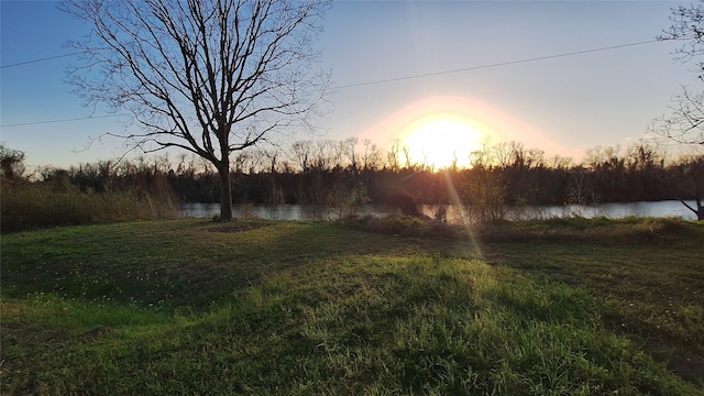 yard at dusk with a forest view and a water view