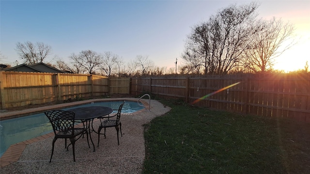pool at dusk featuring a fenced backyard, a yard, and a fenced in pool