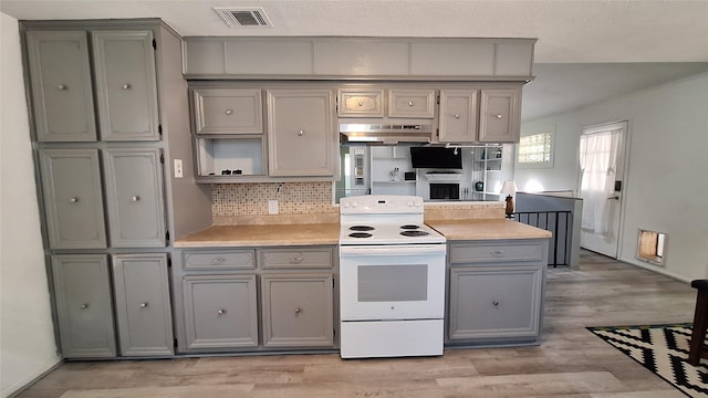 kitchen featuring white range with electric cooktop, gray cabinetry, under cabinet range hood, and light countertops