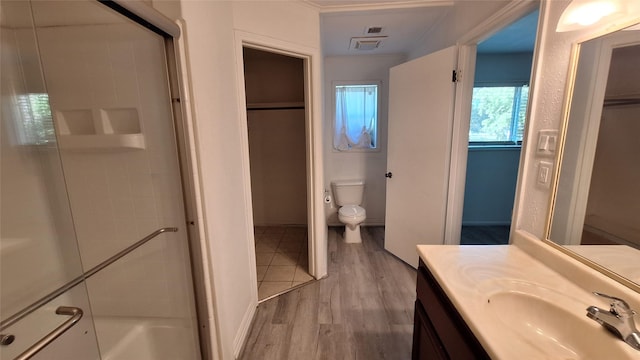 bathroom with a shower, visible vents, toilet, wood finished floors, and vanity