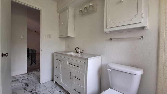 bathroom featuring toilet, marble finish floor, and vanity