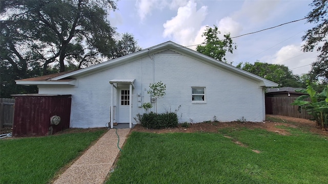 exterior space with brick siding, a yard, and fence