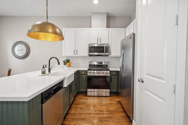 kitchen with light countertops, appliances with stainless steel finishes, a sink, and wood finished floors
