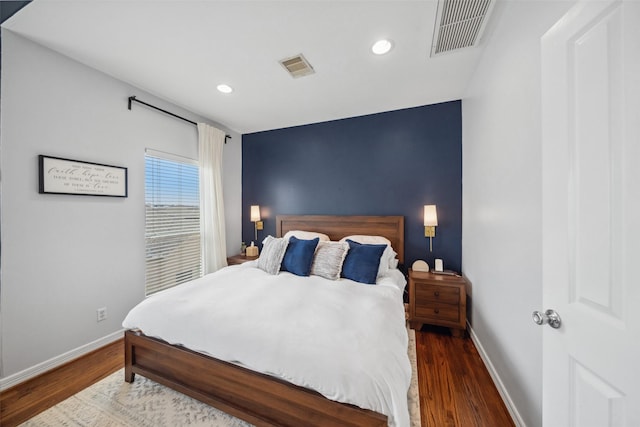 bedroom featuring baseboards, visible vents, and wood finished floors