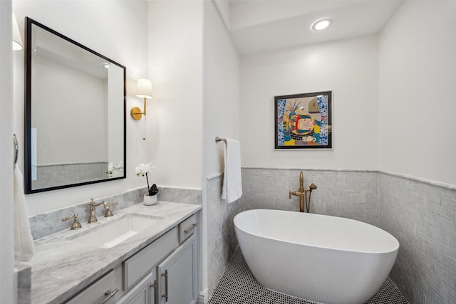 bathroom featuring vanity, tile walls, wainscoting, and a freestanding bath
