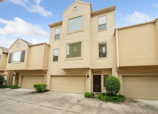 multi unit property featuring concrete driveway, stucco siding, and a garage