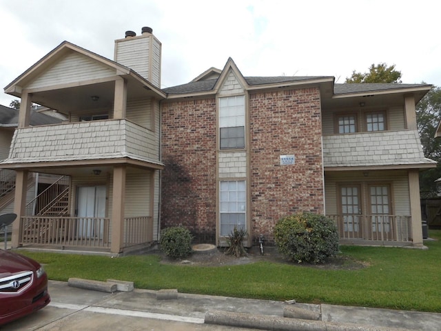 view of front of property with french doors, a balcony, brick siding, and a chimney