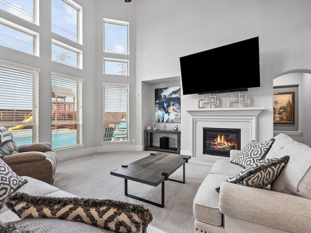 2712 Ahnya Ln, League City, TX 77573 - carpeted living area featuring baseboards, arched walkways, and a glass covered fireplace