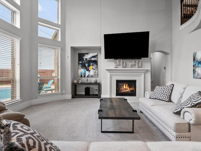 2712 Ahnya Ln, League City, TX 77573 - carpeted living room with plenty of natural light, baseboards, a towering ceiling, and a glass covered fireplace