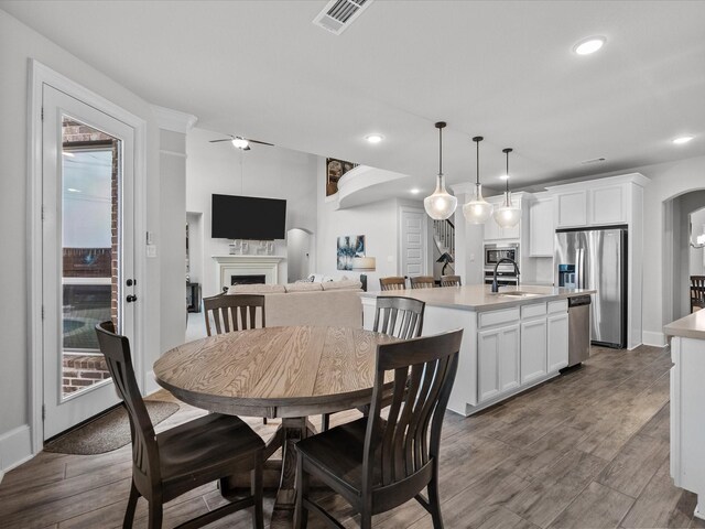 2712 Ahnya Ln, League City, TX 77573 - dining area with recessed lighting, ceiling fan, visible vents, a fireplace, and wood finished floors