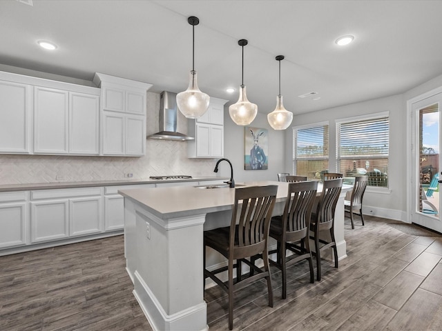 2712 Ahnya Ln, League City, TX 77573 - kitchen featuring dark wood-style flooring, wall chimney exhaust hood, a sink, an island with sink, and backsplash