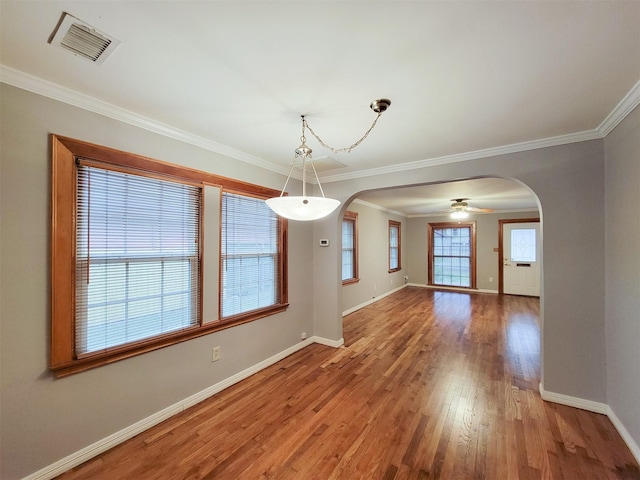 810 E 28th St, Houston, TX 77009 - unfurnished dining area featuring arched walkways, baseboards, visible vents, and wood finished floors