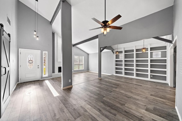 entryway featuring a barn door, wood finished floors, a brick fireplace, visible vents, and ceiling fan