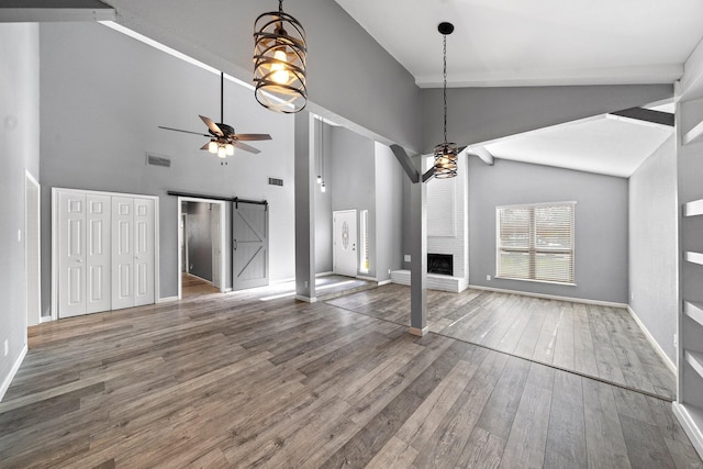 unfurnished living room featuring visible vents, a brick fireplace, a ceiling fan, a barn door, and hardwood / wood-style floors