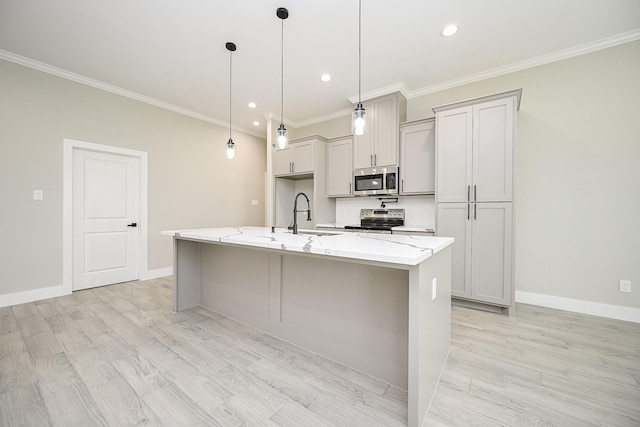 635 Lily St, Prairie View, TX 77484 - kitchen with appliances with stainless steel finishes, ornamental molding, a kitchen island with sink, light stone counters, and light wood finished floors