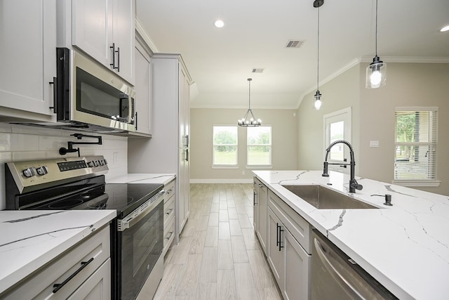 635 Lily St, Prairie View, TX 77484 - kitchen with stainless steel appliances, crown molding, plenty of natural light, backsplash, and a chandelier