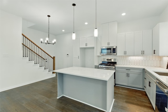 kitchen featuring decorative backsplash, light countertops, a chandelier, stainless steel appliances, and dark wood-type flooring