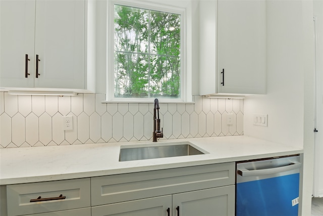 kitchen featuring dishwashing machine, a sink, tasteful backsplash, and light stone countertops