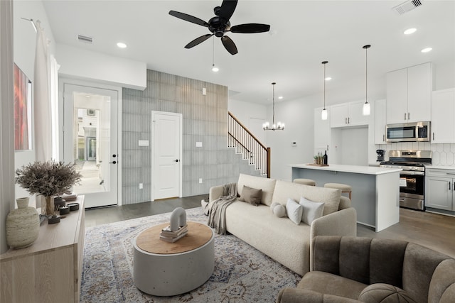 living area with tile walls, recessed lighting, ceiling fan with notable chandelier, dark wood-type flooring, and visible vents