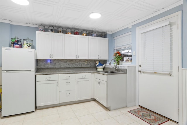 kitchen with a sink, an ornate ceiling, tasteful backsplash, and freestanding refrigerator
