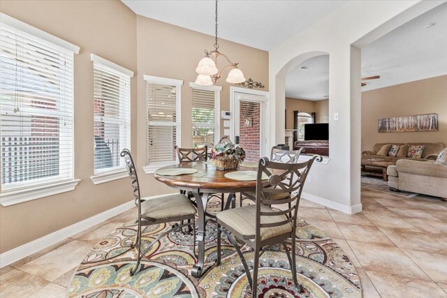2052 Doolan Dr, Conroe, TX 77301 - dining area featuring a chandelier, baseboards, light tile patterned floors, ceiling fan, and arched walkways