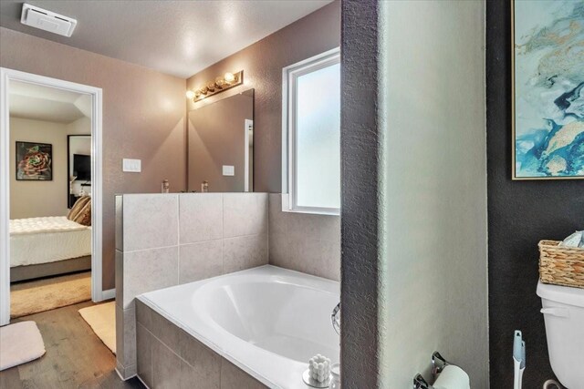 5510 Brooklyn Rose Dr, Rosharon, TX 77583 - ensuite bathroom featuring wood finished floors, a bath, toilet, and a textured wall