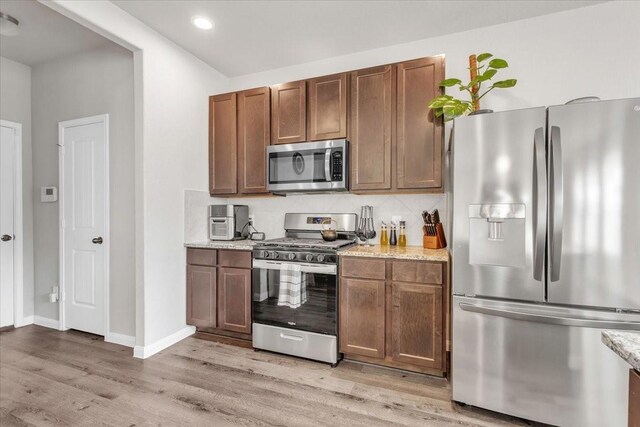 5510 Brooklyn Rose Dr, Rosharon, TX 77583 - kitchen with appliances with stainless steel finishes, light wood finished floors, backsplash, light stone countertops, and recessed lighting