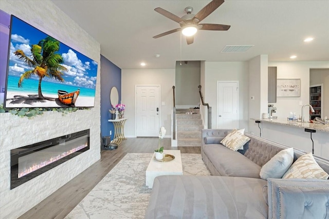 5510 Brooklyn Rose Dr, Rosharon, TX 77583 - living room featuring a stone fireplace, wood finished floors, a ceiling fan, stairway, and recessed lighting