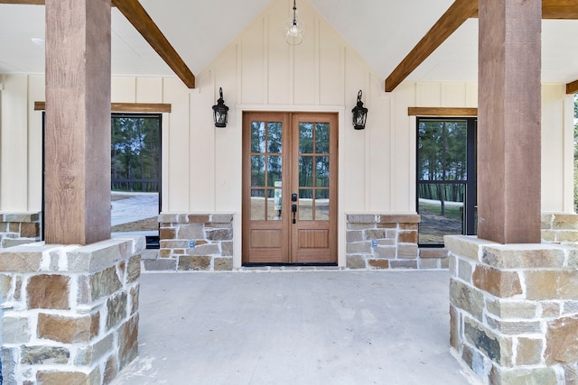 doorway to property featuring french doors, stone siding, and board and batten siding