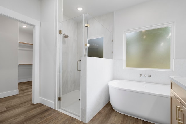 bathroom with vanity, a freestanding tub, a spacious closet, a shower stall, and wood finished floors