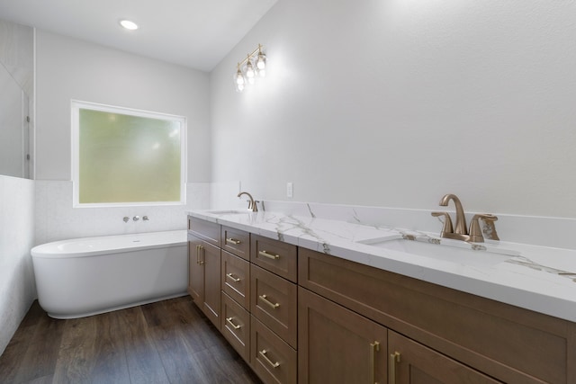 bathroom with double vanity, a sink, a freestanding bath, and wood finished floors