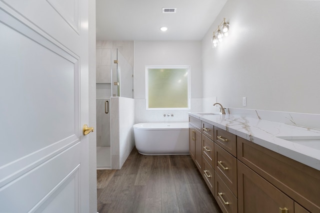 full bath featuring a sink, a shower stall, wood finished floors, a soaking tub, and visible vents