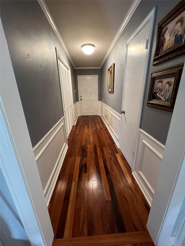 hallway featuring a decorative wall, hardwood / wood-style floors, crown molding, and a wainscoted wall