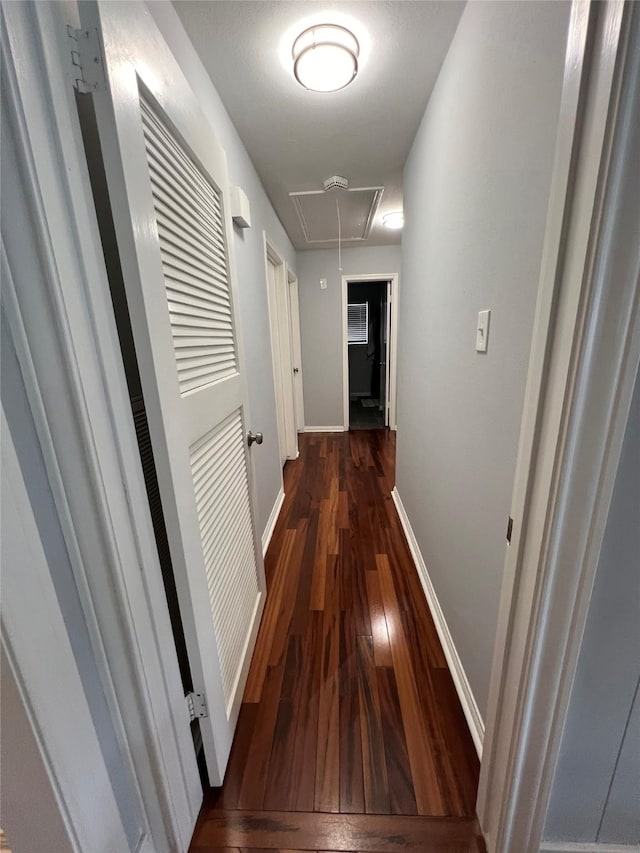corridor with hardwood / wood-style flooring, baseboards, and attic access