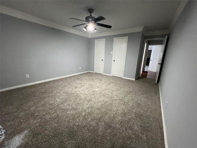 unfurnished bedroom featuring two closets, ceiling fan, ornamental molding, carpet floors, and baseboards