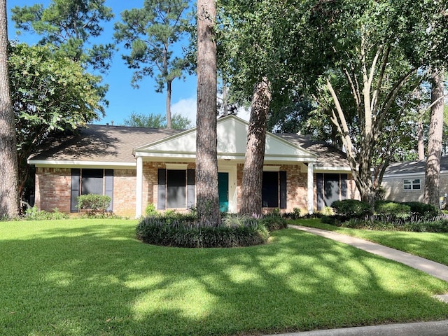 view of front of house featuring brick siding, a front lawn, and a shingled roof