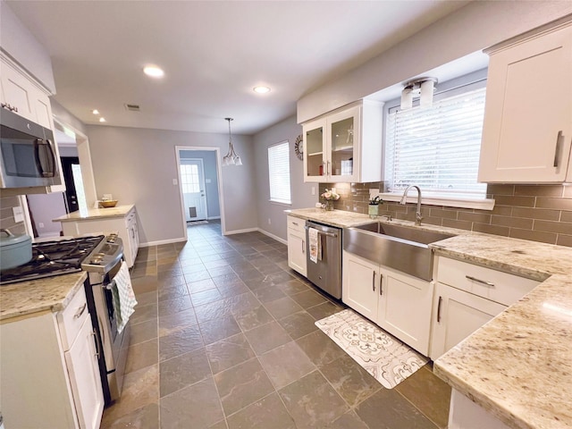 kitchen with tasteful backsplash, white cabinets, a sink, stainless steel appliances, and baseboards