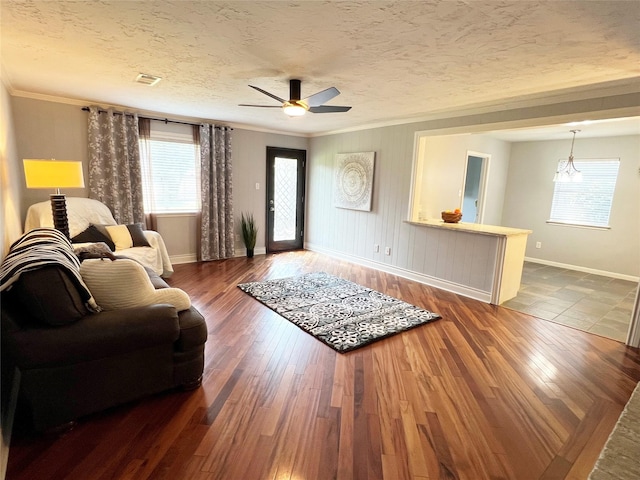 living area featuring baseboards, ornamental molding, visible vents, and a wealth of natural light