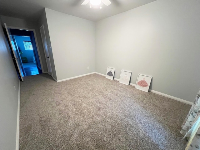 empty room with carpet flooring, baseboards, and a ceiling fan